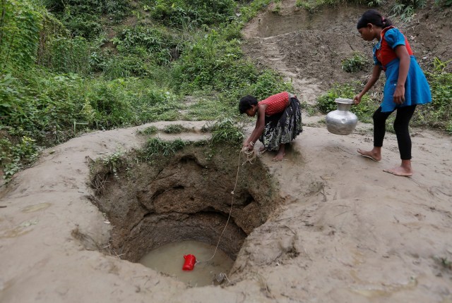 Las niñas refugiadas Rohingya recogen agua de un pozo poco profundo, excavado en la arena del campamento de refugiados de Uchiprang, cerca de Cox's Bazar, Bangladesh 29 de octubre de 2017. REUTERS / Adnan Abidi