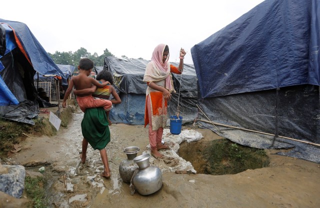 Una niña refugiada rohingya recoge agua de un pozo poco profundo, excavado en la arena detrás de un refugio en el campo de refugiados de Uchiprang cerca de Cox's Bazar, Bangladesh 29 de octubre de 2017. REUTERS / Adnan Abidi