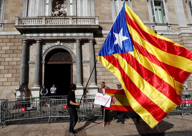 Un hombre con una bandera separatista catalana (L) mira a los hombres que sostienen una bandera española frente al Palacio de la Generalitat, la sede del gobierno regional de Cataluña en Barcelona, España, el 30 de octubre de 2017. REUTERS / Juan Medina