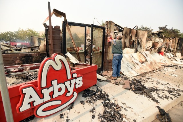 Mike Reynolds of the housing and community services department for the city of Santa Rosa places a red-tag sign on a burned down Arby's restaurant in Santa Rosa, California on October 10, 2017. Firefighters encouraged by weakening winds were battling 17 large wildfires on Tuesday in California which have left at least 13 people dead, thousands homeless and ravaged the state's famed wine country. / AFP PHOTO / JOSH EDELSON