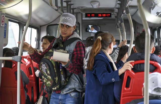 Venezuelan national Jhonger Pina, 25, sells candies and shows Bolivar bills as a curiosity to passengers, in exchange for local coins on a bus in Bogota, on October 26, 2017. Up to October 2017 there were 470,000 Venezuelans in Colombia, who left their country to escape the hardship and violence of its economic and political crisis. / AFP PHOTO / Raul Arboleda / TO GO WITH AFP STORY by Daniela QUINTERO and Santiago TORRADO