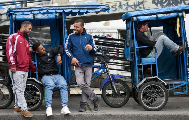 Venezuelan national Gregory Pacheco (3-L), 29, speaks with his compatriots before starting his working day as a "bicitaxi" (pedicab) driver in Bogota, on November 8, 2017. Up to October 2017 there were 470,000 Venezuelans in Colombia, who left their country to escape the hardship and violence of its economic and political crisis. / AFP PHOTO / Raul Arboleda / TO GO WITH AFP STORY by Daniela QUINTERO and Santiago TORRADO