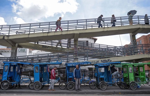 Venezuelan national Gregory Pacheco (Bottom-C), 29, prepares to start his working day as a "bicitaxi" (pedicab) driver in Bogota, on November 8, 2017. Up to October 2017 there were 470,000 Venezuelans in Colombia, who left their country to escape the hardship and violence of its economic and political crisis. / AFP PHOTO / Raul Arboleda / TO GO WITH AFP STORY by Daniela QUINTERO and Santiago TORRADO