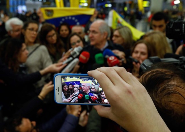 A journalist captures images of the mayor of Caracas, Antonio Ledezma (C) as he speaks to journalists upon his arrival to the Barajas Airport on November 18, 2017 in Madrid. Ledezma arrived from Bogota to Spain on November 18 after escaping house arrest in the Venezuelan capital, after having been accused of conspiracy against the government of Nicolas Maduro. / AFP PHOTO / OSCAR DEL POZO