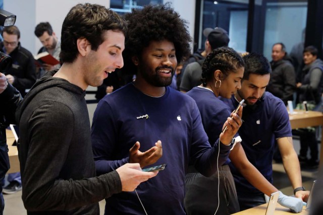 An Apple sales associate speaks with a customer waiting to purchase a new iPhone X in New York, U.S., November 3, 2017. REUTERS/Lucas Jackson