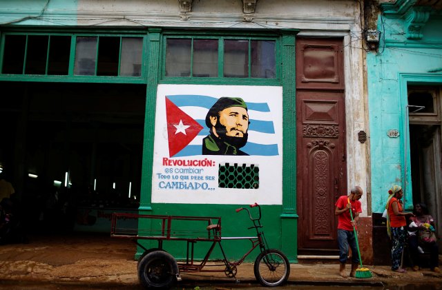 Una pintura que representa al difunto presidente de Cuba, Fidel Castro, que dice en español "Revolución es cambiar todo lo que debe cambiarse" decora una pared fuera de una tienda estatal subsidiada o bodega, donde los cubanos pueden comprar productos básicos con un libro de raciones que reciben anualmente del gobierno, en el centro de La Habana, Cuba, 24 de agosto de 2017. Foto tomada el 24 de agosto de 2017. REUTERS / Alexandre Meneghini NO RESALES. SIN ARCHIVOS.