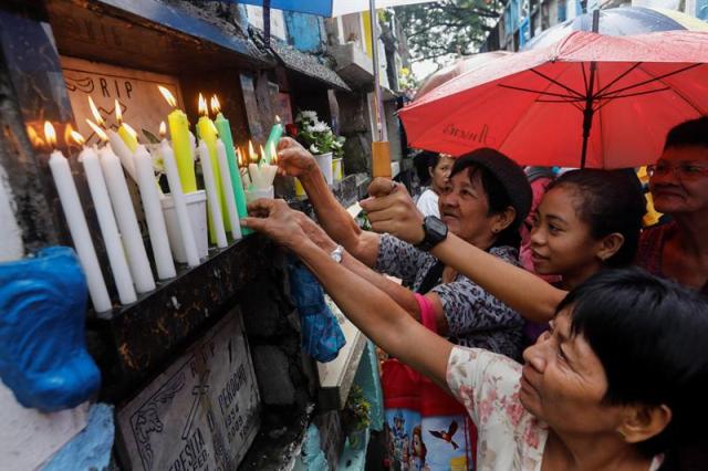 Filipinos encienden velas durante una visita al cementerio público de Quezón, al este de Manila, Filipinas, hoy, 1 de noviembre de 2017. Católicos filipinos siguen la tradición y acuden en los cementerios para recordar a sus familiares fallecidos los días 1 y 2 de noviembre, con motivo del Día de Todos los Santos y el Día de Todas las Almas. Las autoridades reforzaron la seguridad en todo el país para garantizar las visitas y detener posibles actividades delictivas. EFE/ROLEX DELA PENA