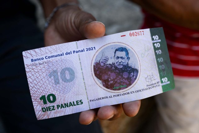 A man shows the new local community currency, the panal, launched in the "23 de Enero" working-class neighbourhood in Caracas on December 15, 2017. A collective in a hilltop shantytown in Caracas created its own currency, the panal, in an attempt to fight chronic shortages of cash in inflation-ridden Venezuela. The currency can be exchanged locally for staples like sugar, rice (produced in the neighborhood itself), and bread. / AFP PHOTO / FEDERICO PARRA