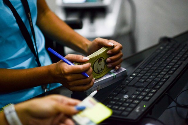 A cashier in the BanPanal communal bank counts notes of the new local community currency, the panal, launched in the "23 de Enero" working-class neighbourhood in Caracas on December 15, 2017. A collective in a hilltop shantytown in Caracas created its own currency, the panal, in an attempt to fight chronic shortages of cash in inflation-ridden Venezuela. The currency can be exchanged locally for staples like sugar, rice (produced in the neighborhood itself), and bread. / AFP PHOTO / FEDERICO PARRA