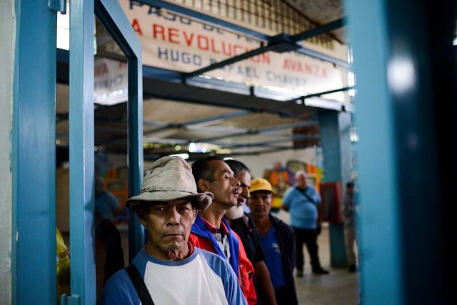 People queue outside the BanPanal communal bank to exchange bolivares for the new local community currency, the panal, launched in the "23 de Enero" working-class neighbourhood in Caracas on December 15, 2017. A collective in a hilltop shantytown in Caracas created its own currency, the panal, in an attempt to fight chronic shortages of cash in inflation-ridden Venezuela. The currency can be exchanged locally for staples like sugar, rice (produced in the neighborhood itself), and bread. / AFP PHOTO / FEDERICO PARRA