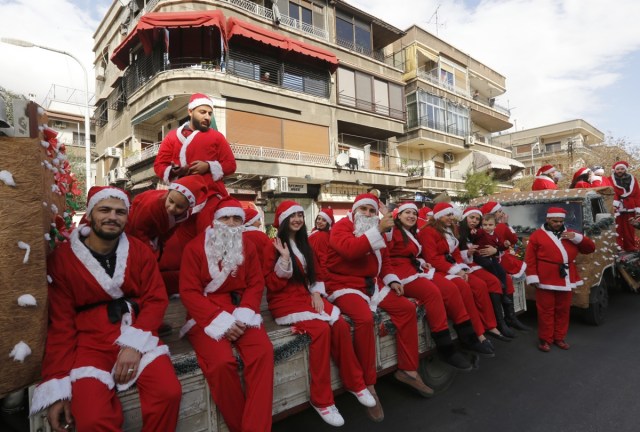 Syrians dressed in Santa Claus outfits roam the streets of the capital Damascus on the back of a decorated vehicle on December 24, 2017 for Christmas eve celebrations. / AFP PHOTO / Louai Beshara