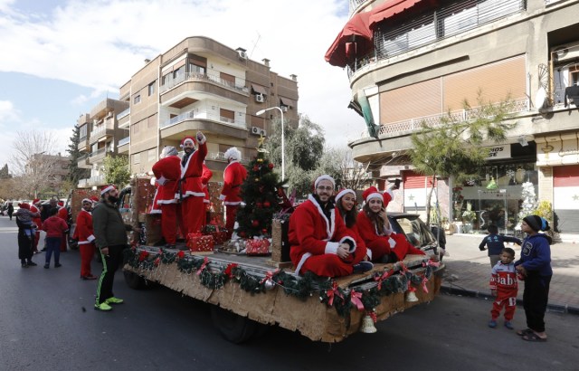 Syrians dressed in Santa Claus outfits roam the streets of the capital Damascus on the back of a decorated vehicle on December 24, 2017 for Christmas eve celebrations. / AFP PHOTO / Louai Beshara