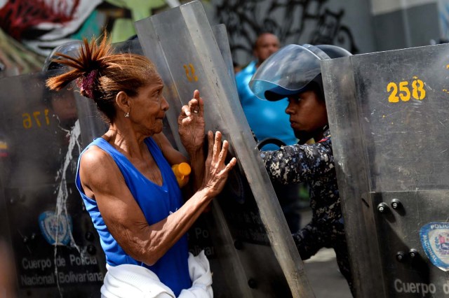 A woman confronts riot police during a protest against the shortage of food, amid Fuerzas Armadas avenue in Caracas on December 28, 2017. As Venezuelans protest in Caracas demanding the government's prommised pork -the main dish of the Christmas and New Year's dinner-, President Nicolas Maduro attributes the shortage to international sabotage. / AFP PHOTO / FEDERICO PARRA