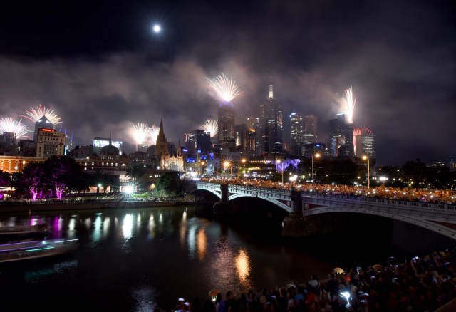 Fireworks light up the sky from building rooftops along the Yarra River during New Year's Eve celebrations in Melbourne early on January 1, 2018. / AFP PHOTO / Mal Fairclough