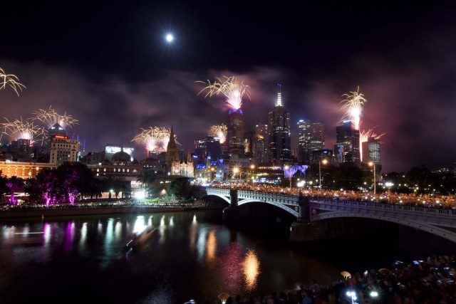 Fireworks light up the sky from building rooftops along the Yarra River during New Year's Eve celebrations in Melbourne early on January 1, 2018. / AFP PHOTO / Mal Fairclough