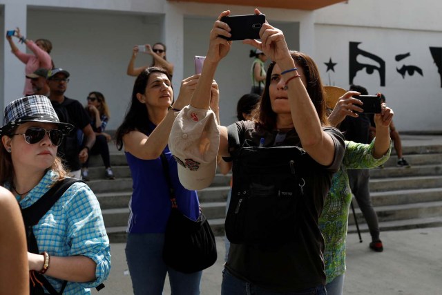 Attendees of a walking tour of 'Caracas in 365' use their phones to take photos in a street at Catia neighborhood in Caracas, Venezuela November 18, 2017. Picture taken November 18, 2017. REUTERS/Marco Bello