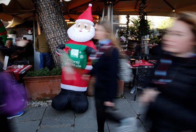 People walk past an inflatable Santa Claus at the Colosseum in Rome, Italy December 17, 2017. REUTERS/Tony Gentile