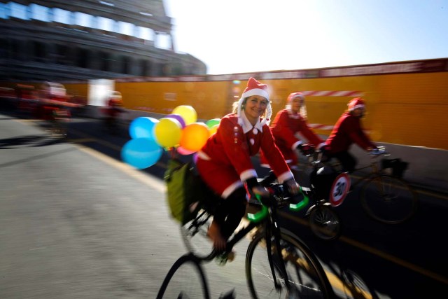 People ride bikes as more than a hundred cyclists dressed as Santa Claus meet at the Colosseum in Rome, Italy December 17, 2017. REUTERS/Tony Gentile