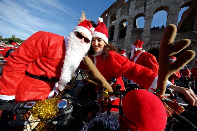 People pose as more than a hundred cyclists dressed as Santa Claus meet at the Colosseum in Rome, Italy December 17, 2017. REUTERS/Tony Gentile