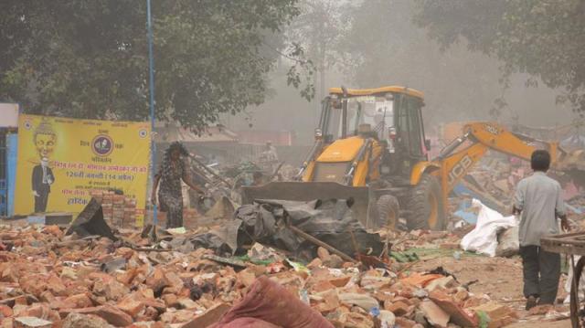 Un habitante del barrio chabolista de Kathputli observa cómo las excavadoras municipales retiran los escombros el 15 de noviembre de 2017 en Nueva Delhi, India. Las chabolas sin agua corriente ni baños del barrio de los titiriteros de Nueva Delhi han dado cobijo a artistas y magos desde hace décadas, pero su reciente demolición por el ayuntamiento ha dejado a sus habitantes divididos entre la esperanza de un futuro mejor y la angustia de quedarse en la calle. La colonia Kathputli, que en hindi significa marioneta, acogía a unas 3.500 familias entre las que había multitud de músicos, bailarines, prestidigitadores y titiriteros, pero también a sirvientes domésticos y trabajadores industriales. Era un barrio con un ambiente mágico pero que no contaba con baños, desagües o agua corriente. Kathputli dejó de existir hace unas semanas cuando las excavadoras de la Autoridad de Desarrollo de Delhi (DDA), un organismo público que controla el desarrollo urbano de la capital india, redujeron las chabolas a escombros. EFE/David Asta