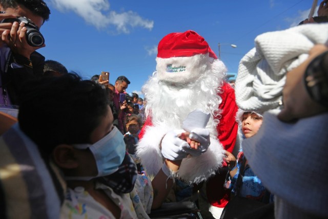 GU301. CIUDAD DE GUATEMALA (GUATEMALA), 20/12/2017.- Un niño que se recupera de una herida de bala desde el 15 de diciembre de 2017 en el Hospital San Juan de Dios le entrega una carta a Santa Claus, en la que le pide al Presidente guatemalteco Jimmy Morales que mejore la seguridad del país hoy, miércoles 20 de diciembre de 2017, en la ciudad de Guatemala (Guatemala). Santa Claus visitó el segundo hospital público más grande de Guatemala para entregar regalos a los niños, actividad que se ha realizado por 34 años consecutivos. EFE/Esteban Biba