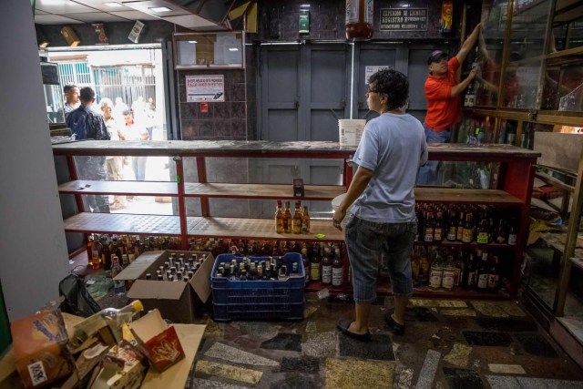 CAR107. CARACAS (VENEZUELA), 28/12/2018.- Un trabajador de una licorera que fue saqueada en horas de la madrugada en el sector La Vega saca productos del local comercial hoy, jueves 28 de diciembre del 2017, en Caracas (Venezuela). Durante la madrugada de este jueves se registraron en varios puntos de Venezuela protestas por la escasez de alimentos para completar el menú navideño, gas y agua, informaron hoy medios locales. EFE/MIGUEL GUTIÉRREZ