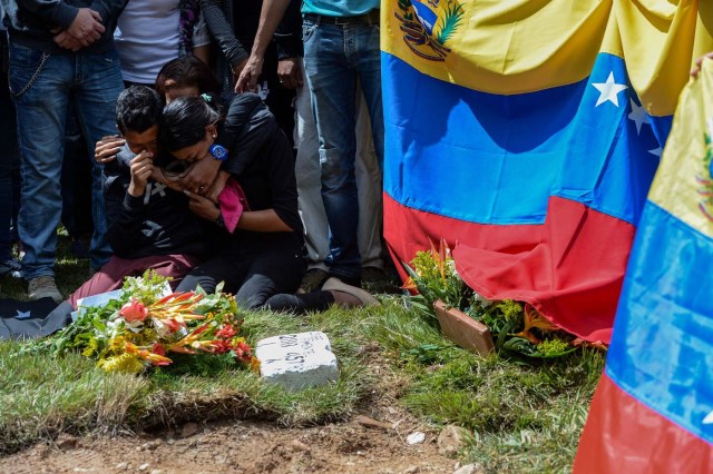 Relatives of Jose Diaz Pimentel, one of the six other dissidents gunned down along with former elite police officer Oscar Perez in a bloody police operation, cry next to his grave as he and rebel Abraham Agostini are buried at a cemetery in Caracas on January 20, 2018. Perez, Venezuela's most wanted man since he flew a stolen police helicopter over Caracas dropping grenades on the Supreme Court and opening fire on the Interior Ministry, had gone on social media while the operation was under way on January 16 to say he and his group wanted to surrender but were under unrelenting sniper fire. That has raised questions about the government's account that the seven were killed after opening fire on police who had come to arrest them. / AFP PHOTO / Federico PARRA