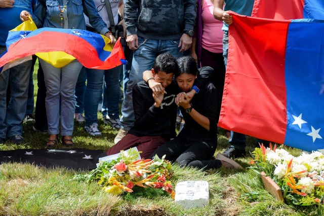 Relatives of Jose Diaz Pimentel, one of the six other dissidents gunned down along with former elite police officer Oscar Perez in a bloody police operation, cry next to his grave as he and rebel Abraham Agostini are buried at a cemetery in Caracas on January 20, 2018. Perez, Venezuela's most wanted man since he flew a stolen police helicopter over Caracas dropping grenades on the Supreme Court and opening fire on the Interior Ministry, had gone on social media while the operation was under way on January 16 to say he and his group wanted to surrender but were under unrelenting sniper fire. That has raised questions about the government's account that the seven were killed after opening fire on police who had come to arrest them. / AFP PHOTO / Federico PARRA