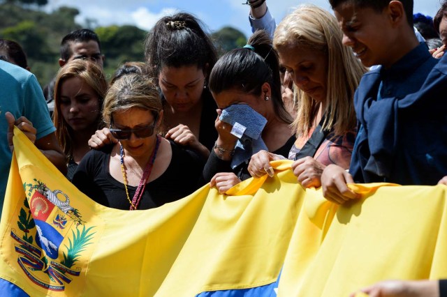 Relatives and friends of Jose Diaz Pimentel and Abraham Agostini, two of the six other dissidents gunned down along with former elite police officer Oscar Perez in a bloody police operation, attend their funeral at a cemetery in Caracas on January 20, 2018. Perez, Venezuela's most wanted man since he flew a stolen police helicopter over Caracas dropping grenades on the Supreme Court and opening fire on the Interior Ministry, had gone on social media while the operation was under way on January 16 to say he and his group wanted to surrender but were under unrelenting sniper fire. That has raised questions about the government's account that the seven were killed after opening fire on police who had come to arrest them. / AFP PHOTO / Federico PARRA