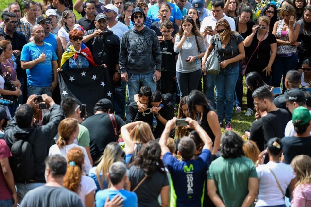 Activists opposing Venezuelan President Nicolas Maduro join relatives and friends of Jose Diaz Pimentel and Abraham Agostini, two of the six other dissidents gunned down along with former elite police officer Oscar Perez in a bloody police operation, during their funeral at a cemetery in Caracas on January 20, 2018. Perez, Venezuela's most wanted man since he flew a stolen police helicopter over Caracas dropping grenades on the Supreme Court and opening fire on the Interior Ministry, had gone on social media while the operation was under way on January 16 to say he and his group wanted to surrender but were under unrelenting sniper fire. That has raised questions about the government's account that the seven were killed after opening fire on police who had come to arrest them. / AFP PHOTO / Federico PARRA