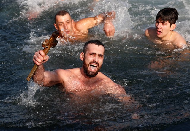 Greek Orthodox faithful Nikolas Solis, a pilgrim from Greece, reaches out to retrieve a wooden crucifix as he swims in the Golden Horn in Istanbul, Turkey, January 6, 2018. REUTERS/Murad Sezer