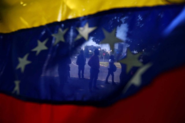 Demonstrators are seen through a Venezuelan flag during a rally against Venezuela's government as members of Lima Group nations meet in Santiago, Chile January 23, 2018. REUTERS/Ivan Alvarado