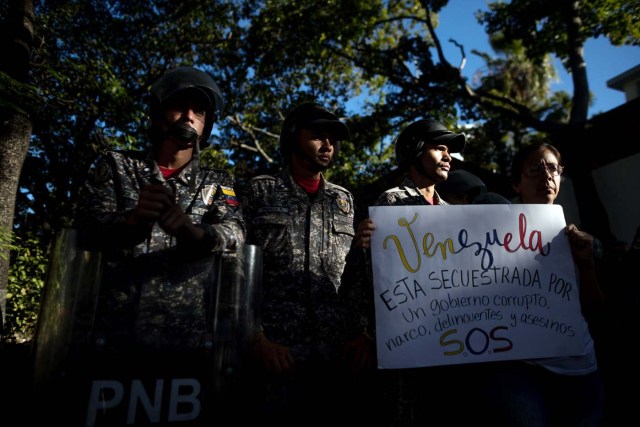 CAR206. CARACAS (VENEZUELA), 20/01/2018.- Miembros de la Policía Nacional Bolivariana (PNB) custodian las inmediaciones de la morgue mientras personas protestan en apoyo a los familiares de Oscar Pérez hoy, sábado 20 de enero del 2018, en Caracas (Venezuela). Cientos de venezolanos honraron hoy al exinspector de la Policía científica Óscar Pérez y a sus seis compañeros, que murieron el lunes en una operación policial, en medio de la tensión que ha generado la entrega del cuerpo del líder del grupo que se alzó contra el Gobierno de Nicolás Maduro. EFE/Miguel Gutiérrez