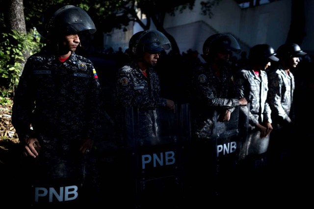 CAR204. CARACAS (VENEZUELA), 20/01/2018.- Miembros de la Policía Nacional Bolivariana (PNB) custodian las inmediaciones de la morgue mientras personas protestan en apoyo a los familiares de Oscar Pérez hoy, sábado 20 de enero del 2018, en Caracas (Venezuela). Cientos de venezolanos honraron hoy al exinspector de la Policía científica Óscar Pérez y a sus seis compañeros, que murieron el lunes en una operación policial, en medio de la tensión que ha generado la entrega del cuerpo del líder del grupo que se alzó contra el Gobierno de Nicolás Maduro. EFE/Miguel Gutiérrez