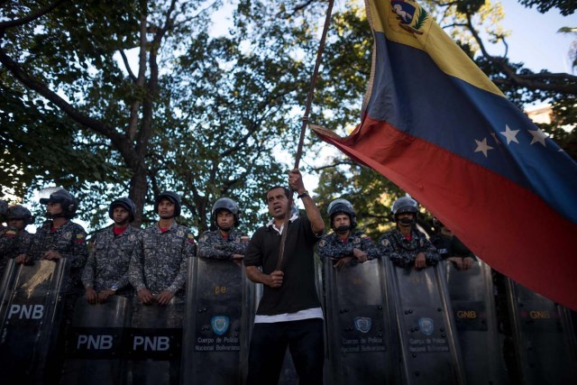 CAR207. CARACAS (VENEZUELA), 20/01/2018.- Miembros de la Policía Nacional Bolivariana (PNB) custodian las inmediaciones de la morgue mientras personas protestan en apoyo a los familiares de Oscar Pérez hoy, sábado 20 de enero del 2018, en Caracas (Venezuela). Cientos de venezolanos honraron hoy al exinspector de la Policía científica Óscar Pérez y a sus seis compañeros, que murieron el lunes en una operación policial, en medio de la tensión que ha generado la entrega del cuerpo del líder del grupo que se alzó contra el Gobierno de Nicolás Maduro. EFE/Miguel Gutiérrez