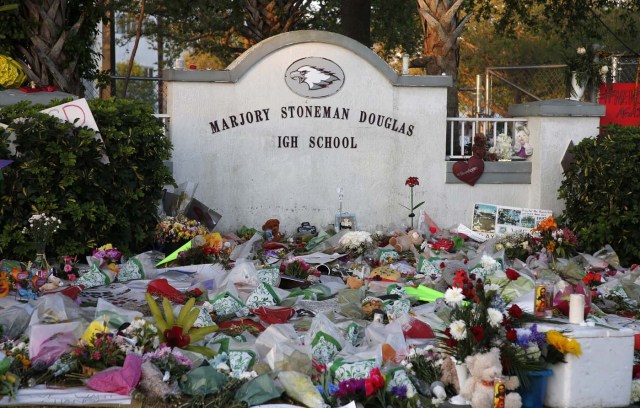 Flowers, candles and mementos sit outside one of the makeshift memorials at Marjory Stoneman Douglas High School in Parkland, Florida on February 27, 2018. Florida's Marjory Stoneman Douglas high school will reopen on February 28, 2018 two weeks after 17 people were killed in a shooting by former student, Nikolas Cruz, leaving 17 people dead and 15 injured on February 14, 2018. / AFP PHOTO / RHONA WISE