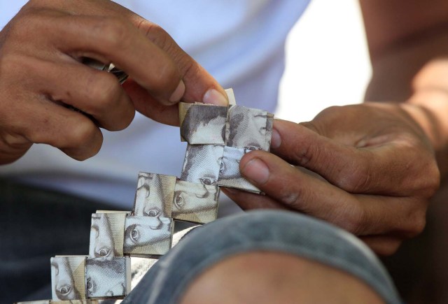 Un hombre dobla billetes de banco venezolanos para hacer un bolso, en Maicao, Colombia el 16 de febrero de 2018. Fotografía tomada el 16 de febrero de 2018. REUTERS / Jaime Saldarriaga