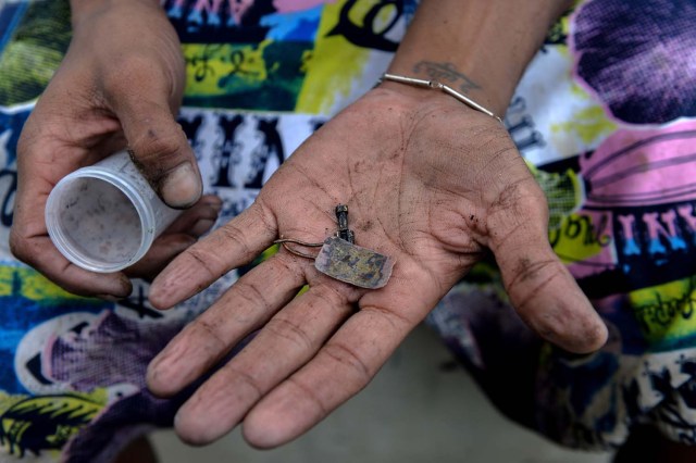 Un hombre muestra objetos encontrados después de recoger el barro del fondo del canal de aguas residuales en el río Guaire en Caracas, el 1 de febrero de 2018. Decenas de jóvenes buscan diariamente joyas perdidas en el río Guaire, donde drenan las alcantarillas de Caracas. Encontrar oro es su ilusión, pero una pieza de alambre de cobre es suficiente para paliar el hambre. / AFP PHOTO / FEDERICO PARRA