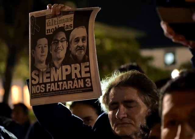 Un hombre sostiene un periódico durante un homenaje al periodista asesinado ecuatoriano Javier Ortega, al fotógrafo Paul Rivas y a su chofer Efraín Segarra, frente a la Catedral Metropolitana, en Quito el 13 de abril de 2018. Los tres miembros de un equipo de periodistas ecuatorianos que murieron en cautiverio después de ser secuestrados por un grupo rebelde colombiano estaban siguiendo una historia sobre la violencia que terminó costando sus vidas. / AFP PHOTO / RODRIGO BUENDIA