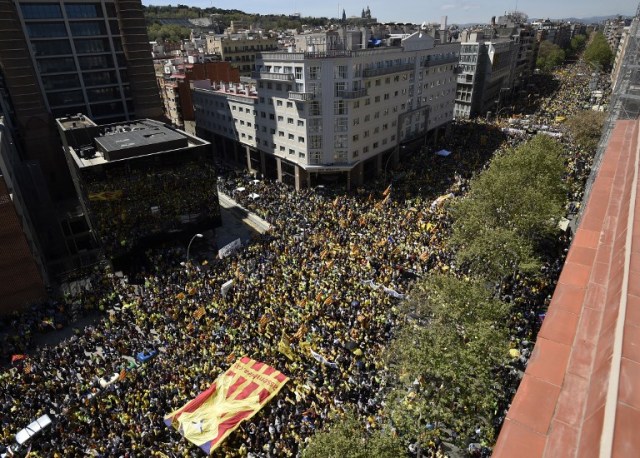 People carry a big Catalan pro-independence 'estelada' flag with a yellow ribbon on it during a demonstration to support Catalan pro-independence jailed leaders and politicians and called by 'Espai Democracia i Convivencia' platform that groups separatist collectives and unions in Barcelona on April 15, 2018.  Thousands of people marched in Barcelona today to protest the jailing of nine Catalan separatist leaders facing trial on "rebellion" charges. Many chanted "Freedom for the political prisoners" as they massed on the Parallel Avenue, one of the city's main streets, wearing yellow scarves, sweaters or jackets -- the colour chosen to show solidarity with the jailed leaders.  / AFP PHOTO / Josep LAGO