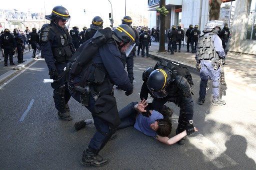 La policía antidisturbios de CRS detiene a un hombre durante enfrentamientos en una manifestación el 19 de abril de 2018 en París, como parte de un día de protestas de varias ramas convocado por los sindicatos franceses CGT y Solidaires contra las políticas del presidente francés en medio de una huelga ferroviaria sentadas. El presidente de Francia se enfrentó a protestas masivas el 19 de abril cuando los sindicalistas buscan galvanizar a los estudiantes enojados, los trabajadores del sector público y los conductores de trenes en huelga en un movimiento conjunto en contra de su impulso múltiple para reformar la economía francesa. / AFP PHOTO / Zakaria ABDELKAFI