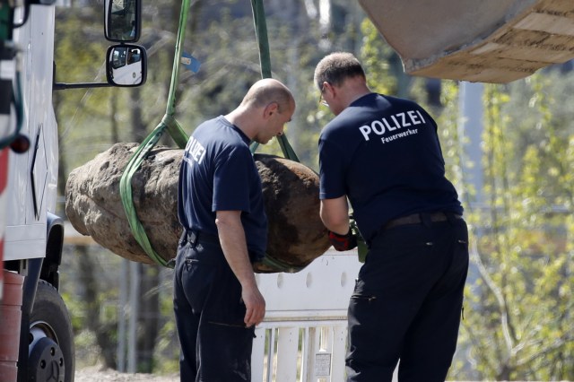 Policías alemanes se paran junto a una bomba lanzada durante la Segunda Guerra Mundial, ya que se levanta con una excavadora durante la operación de eliminación el 20 de abril de 2018 en Berlín. Miles de personas alrededor de la estación central de trenes de Berlín fueron evacuados mientras los expertos en desactivación de explosivos desactivaron un explosivo sin explotar de la Segunda Guerra Mundial desenterrado en una obra en el distrito Mitte de Berlín. / AFP PHOTO / Odd ANDERSEN