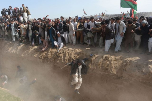 Partidarios del candidato presidencial afgano Ashraf Ghani saltan para cruzar una zanja tras una reunión en las afueras de la provincia de Kunduz, al norte de Kabul, el 19 de marzo de 2014. SHAH MARAI AFP