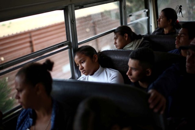 Members of a caravan of migrants from Central America ride on a bus past the border fence between Mexico and the U.S., to gather in a park prior to preparations for an asylum request in the U.S., in Tijuana, Mexico April 29, 2018. REUTERS/Edgard Garrido