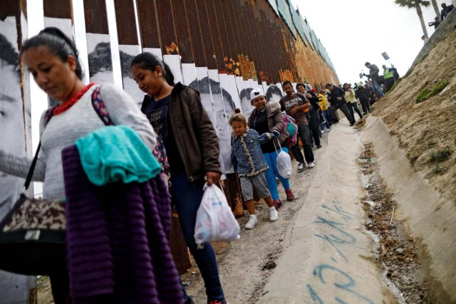 Members of a caravan of migrants from Central America walk next to the border fence between Mexico and the U.S., before a gathering in a park and prior to preparations for an asylum request in the U.S., in Tijuana, Mexico April 29, 2018. REUTERS/Edgard Garrido