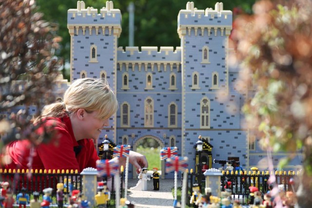 Legoland employee, Lucy, poses putting a Lego model of US actress Meghan Markle (L) in place next to her husband-to-be Britain's Prince Harry (R) outside a Lego-brick model of Windsor Castle at Legoland in Windsor on May 8, 2018 during a photo call for its attraction celebrating the upcoming royal wedding. Prince Harry and US actress Meghan Markle will marry on May 19 at St. George's Chapel at Windsor Castle. / AFP PHOTO / Daniel LEAL-OLIVAS