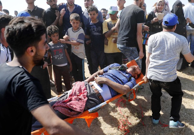 Los palestinos llevan a un manifestante herido durante enfrentamientos con fuerzas israelíes cerca de la frontera entre Gaza e Israel al este de la ciudad de Gaza el 14 de mayo de 2018, mientras los palestinos protestan por la inauguración de la embajada de Estados Unidos tras su controvertido traslado a Jerusalén. Docenas de palestinos fueron asesinados por disparos israelíes el 14 de mayo cuando decenas de miles protestaron y estallaron enfrentamientos a lo largo de la frontera de Gaza contra la transferencia de su embajada a Jerusalén, luego de meses de protestas globales, ira palestina y elogios exuberantes de los israelíes por el presidente Donald Trump decisión dejando de lado décadas de precedentes. / AFP PHOTO / Thomas COEX