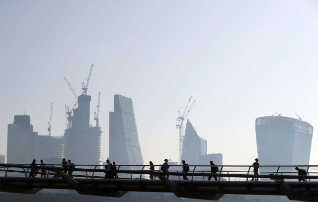 FILE PHOTO: People cross the Millenium Bridge in front of the City on a sunny morning in London, Britain, May 8, 2018. REUTERS/Hannah McKay/File Photo