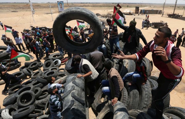 Palestinians collect tires to be burnt during a protest marking the 70th anniversary of Nakba, at the Israel-Gaza border in the southern Gaza Strip May 15, 2018. REUTERS/Ibraheem Abu Mustafa