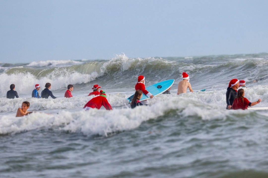 En tablas de surf, Papás Noel toman playa en Florida por diversión y una buena causa (FOTOS)